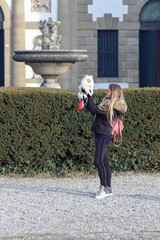 Beautiful young smiling girl strolls with small white dog. German dwarf Spitz. Pomeranian.