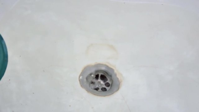 handyman plumber cleaning blockage in bath sink with plunger