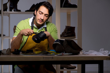 Young shoemaker in workshop at night 