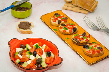 Italian antipasto. Crispy baked crostinis with tomatoes and mozzarella and olive pate next to a fresh vegetable salad  