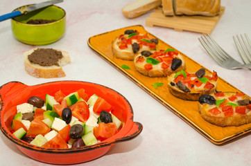 Italian antipasto. Crispy baked crostinis with tomatoes and mozzarella and olive pate next to a fresh vegetable salad  