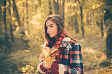 Fototapeta na wymiar Outdoors lifestyle fashion portrait of pretty young woman walking on the autumn park. Outdoor atmospheric fashion photo of young beautiful lady in autumn landscape.