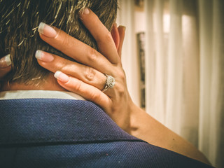 Closeup Of Diamond Engagement Ring and Engaged Couple