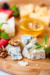 dorblu slices close up. Cheese plate served with berries, walnuts and honey. delicious snack on wooden platter
