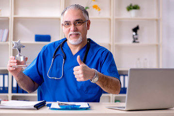 White bearded old doctor working in clinic 