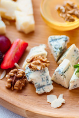 dorblu slices close up. Cheese plate served with berries, walnuts and honey. delicious snack on wooden platter
