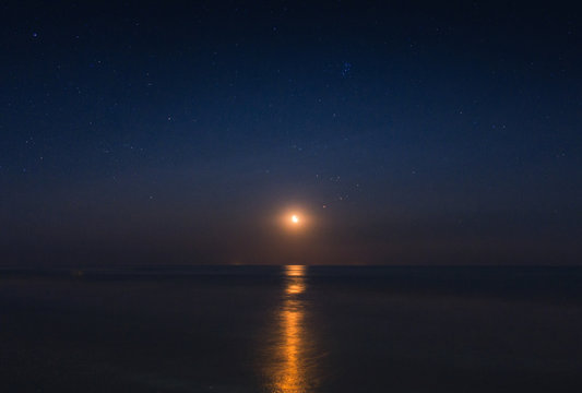 Full moon reflected in the starry night in the waves of the sea