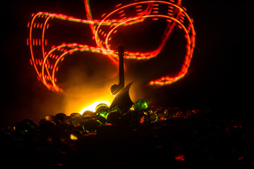 Music concept. Acoustic guitar isolated on a dark background under beam of light with smoke with copy space. Guitar Strings, close up. Selective focus. Fire effects. Surreal guitar