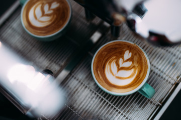 A cup of latte art is on coffee machine.