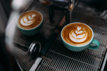 A cup of latte art is on coffee machine.