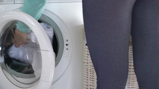 Woman loads the laundry in the washing machine