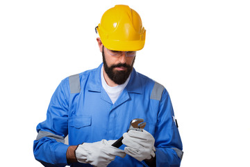 A man, a worker, in a yellow helmet and blui uniform looking at steel adjustable spanner, over white background