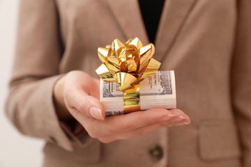 Woman holding bundle of dollars tied with ribbon, closeup