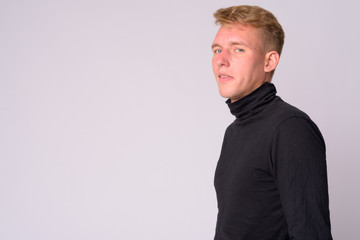 Profile view of young blonde man looking at camera