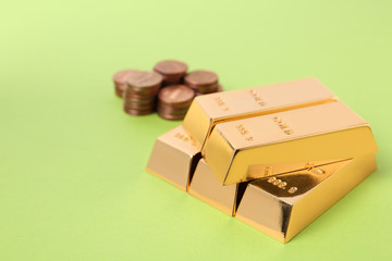 Stacked gold bars and coins on color background. Space for text