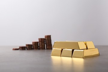 Obraz premium Stacked gold bars and coins on table. Space for text