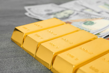 Gold bars and dollar bills on table, closeup