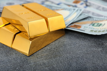 Stacked gold bars and dollar bills on table, closeup. Space for text
