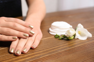 Obraz na płótnie Canvas Woman with gold manicure at table, closeup. Nail polish trends
