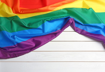 Bright rainbow gay flag on wooden background, top view with space for text. LGBT community
