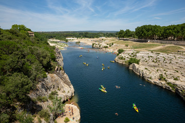 Obraz premium Kayaking and canoeing under the arches of teh Pont du Gard in France on a hot summer day