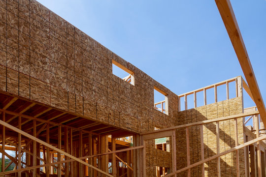 Looking up new construction beams under a clear blue sky with sunlight