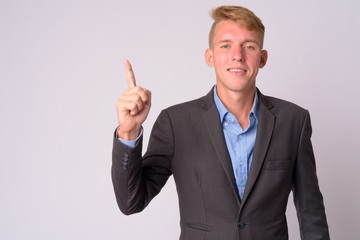 Happy young blonde businessman with suit pointing up