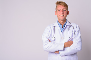 Portrait of happy young blonde man doctor with arms crossed