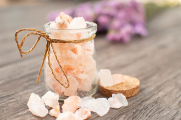 himalayan salt in bottle on wooden background with purple flower , spa and relaxing concept