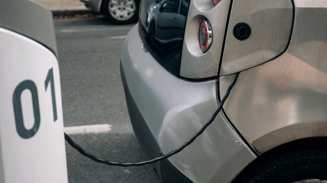 Detail - an electrocar with a charging cord, connecting it to a charger