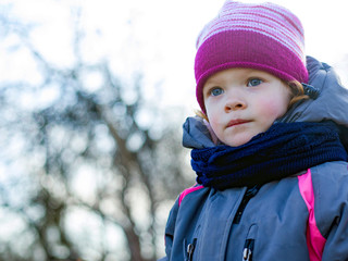 redhead beautiful little girl warmly dressed and wrapped in a scarf playing outside