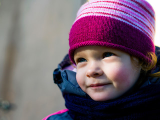 happy red-haired little girl smiling outdoors portrait close-up in warm outerwear