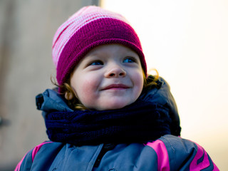 happy red-haired little girl smiling outdoors portrait close-up in warm outerwear