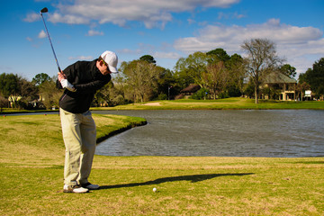 Golfer taking practice swings on the tee box with ball and hole in the frame