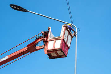 Technician on bucket truck high up of a crane to fix street light.
