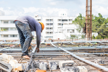 Worker install wire on building floor for tower under construction site.