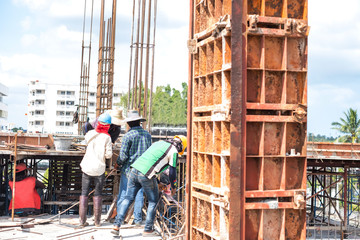 Workers collaborating in the installation of cement formwork frames at construction site.