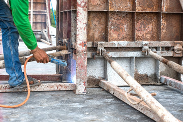 Welder worker welding steel structure outdoor at building construction site without protection.