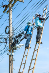 Electrician climbing the bamboo ladder to repair electric wires.