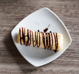 Delicious crepe roll with chocolate hazelnut spread on wooden table. Top view.