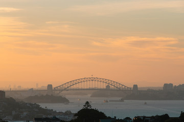 Sydney Harbour Bridge with orange sky at sunset time.