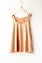 ハンガーにかけたベージュオレンジのタンクトップ