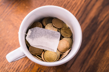 Teabag in a teacup on top of coins