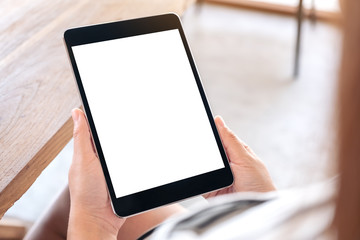 Mockup image of a woman sitting and holding black tablet pc with blank white desktop screen