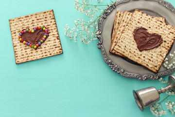 Pesah celebration concept (jewish Passover holiday) with chocolate heart and colorful candies over matzah. Top view flat lay