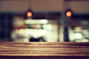 Image of wooden table in front of abstract blurred restaurant lights background