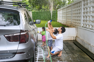 Asian father washing a car with his children