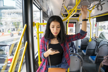 Asian woman with phone inside the bus