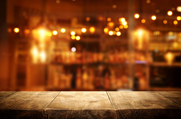 Image of wooden table in front of abstract blurred restaurant lights background