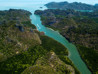 Aerial view of bay and river in Park Kilim Geoforest, Langkawi, Malaysia. Beautiful mountains, sea and trees around the river. Boat sailing on the river